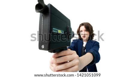 Beautiful girl brunette on a white background shoots selfies of an old vintage movie camera in super 8 format, in isolation. Photo with a shallow depth of field, sharpness on the lens.