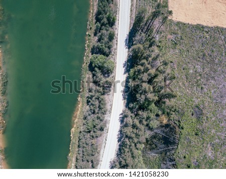 aerial drone view of green lake in forest area with road network in summer