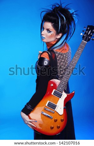 Back of Rock emo girl posing with electric guitar isolated on blue background