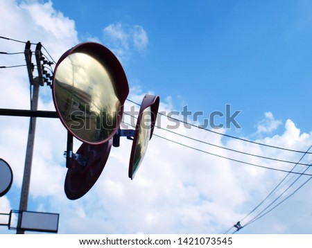 Curved glass, traffic curved glass, mirror, intersection or curved track. For the safety of the driver, the angle can be seen. With copy space On the background of a blue sky with white clouds.