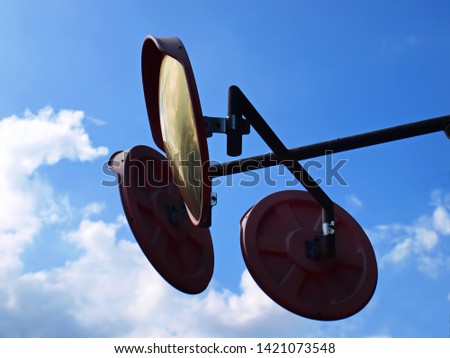 Curved glass, traffic curved glass, mirror, intersection or curved track. For the safety of the driver, the angle can be seen. With copy space On the background of a blue sky with white clouds.