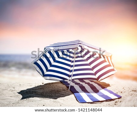 Summer background of beach with sunset time. Sand of yellow color with free space for your decoration. White and dark blue color of umbrella. Warm sunny day. 