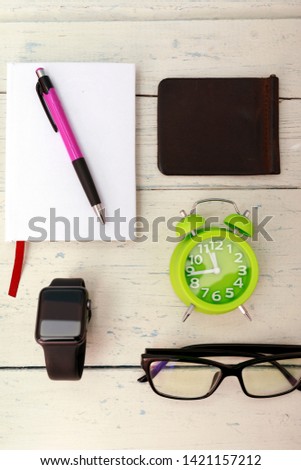 Notepad with pen, smarth watch and phone, sneakers on shabby white wooden background in high quality.
