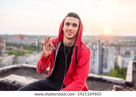 Manly but romantic sport man taking a smartphone or mobile phone photo or picture of sunset on a city rooftop after training