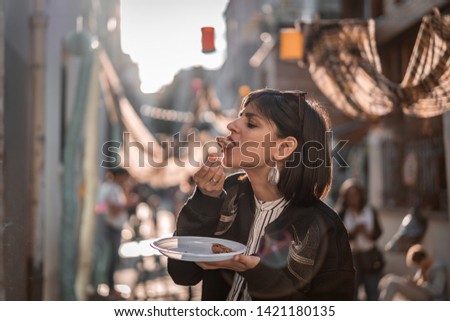 Beautiful young female tourist in city of Paris France enjoying holidays in beautiful little street festival eating street food Royalty-Free Stock Photo #1421180135