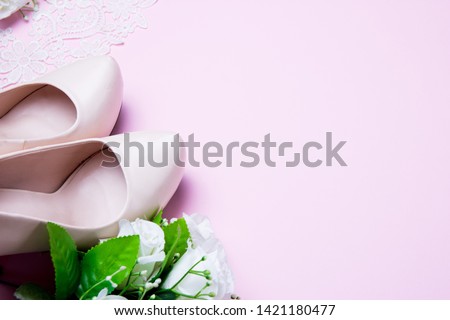 Wedding shoes and bouquet lying on pink background. Close up. flat lay. top view.