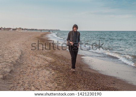 A woman photographer walks along the sea, ocean coast. Summer tourism, photographing attractions on vacation.