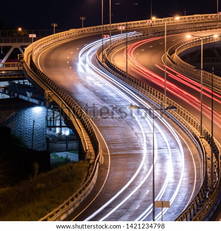 Interchange bridge road with car light streaks. Night light painting stripes. Long exposure photography.