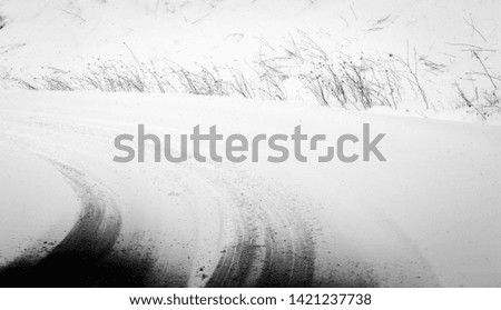 Tracks of car tires on snowy road. Background. Abstract. Black and white.