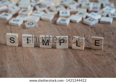 simple, simple word written with cube letters on wooden table or background or surface. concept photo with profile view of small wood cubic letters or alphabets on table with copy space