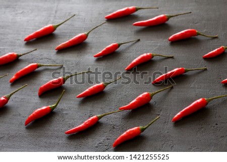 Red Hot Chili Peppers On Black Dark Background on Black Table. A Lot of Red Chilli Peppers. Copy space for your text. Flat lay, top view. Rhythmic image, repetition of a picture or objects in a photo.