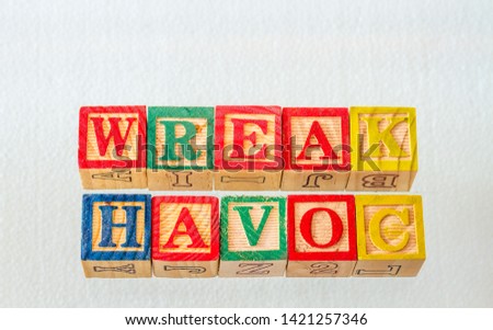 The term wreak havoc visually displayed using colorful wooden blocks on a clear background image with copy space in landscape format
