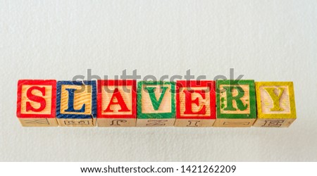 The term slavery visually displayed using colorful wooden blocks on a clear background image with copy space in landscape format