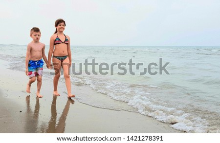 children are walking on the shore
