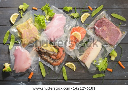 Sous Vide cooking concept. Vacuum packed ingredients arranged on wooden dyed background. Top View. Royalty-Free Stock Photo #1421296181