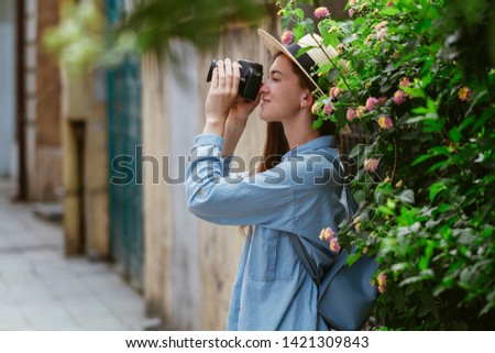 Photographer traveler in hat takes pictures of sights while walking along the street of a european city. Vacation and tourism 