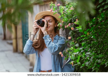 Photographer traveler in hat takes pictures of sights while walking along the street of a european city. Vacation and traveling lifestyle 