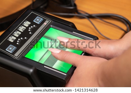 The process of scanning fingerprints during the check at border crossing. Female hand puts fingers to the fingerprint scanner. Biometric, identity verification and border control, immigration concept Royalty-Free Stock Photo #1421314628