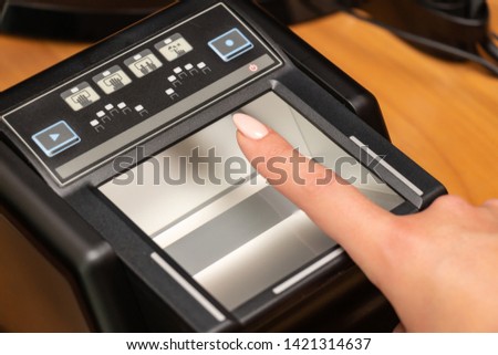 The process of scanning fingerprints during the check at border crossing. Female hand puts fingers to the fingerprint scanner. Biometric, identity verification and border control, immigration concept Royalty-Free Stock Photo #1421314637