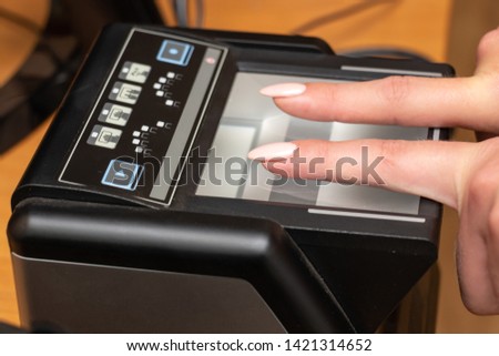 The process of scanning fingerprints during the check at border crossing. Female hand puts fingers to the fingerprint scanner. Biometric, identity verification and border control, immigration concept Royalty-Free Stock Photo #1421314652