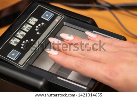 The process of scanning fingerprints during the check at border crossing. Female hand puts fingers to the fingerprint scanner. Biometric, identity verification and border control, immigration concept Royalty-Free Stock Photo #1421314655