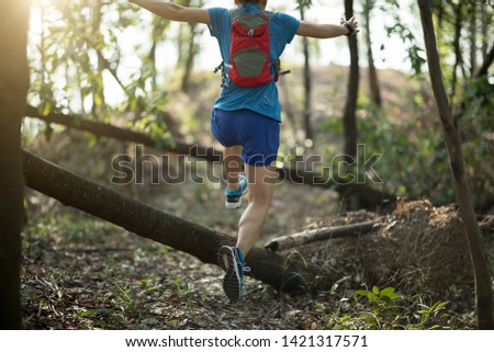 Sportswoman ultramarathon cross country trail running in tropical autumn forest Royalty-Free Stock Photo #1421317571