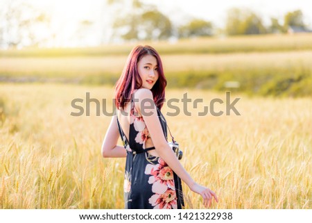 Charming asian woman in wheat field with soft sunset