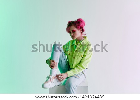 woman with pink hair sits on a neon retro cube