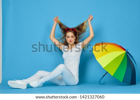   woman sitting on the floor with an umbrella on a blue background                             