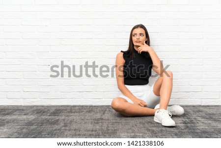 Pretty young woman sitting on the floor thinking