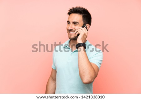 Handsome young man over isolated background keeping a conversation with the mobile phone