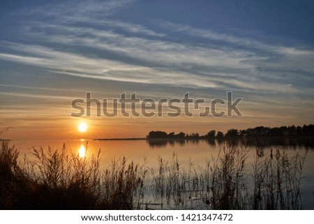 cloudy sunset with beautiful colors and scenery. water in the foreground and orange lighting