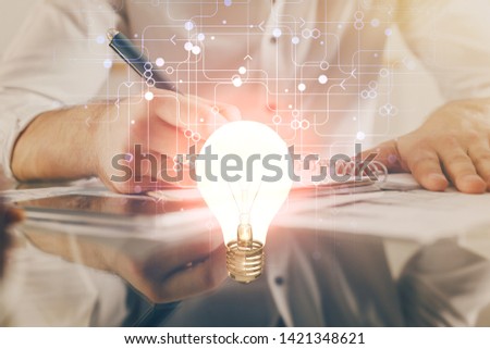 View of Bulb lamp idea concept icon on a futuristic interface with writing man's hand background. Double exposure.