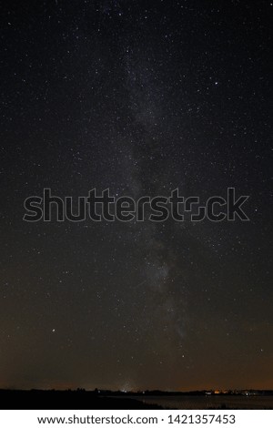 milky way portrait shot with small city underneath