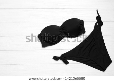 Stylish bikini and space for text on wooden background, flat lay