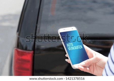 Woman with smartphone and german translation for sale of cars