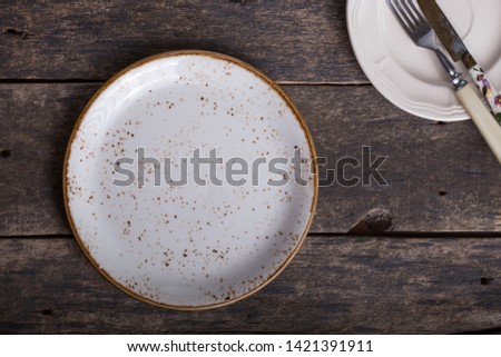 Empty white plate  on an old wooden brown background, top view. Image with copy space. 