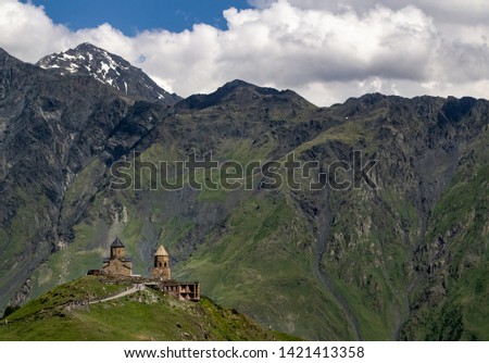 A picture of the Gergeti Trinity Church in Stepantsminda, Georgia with the mountain range behind.