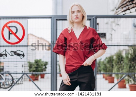A stylish young girl, a doctor or a nurse poses for the advertising photography of a medical shirt for medical staff, comfortable and stylish clothes. urban clothing style. Street photography