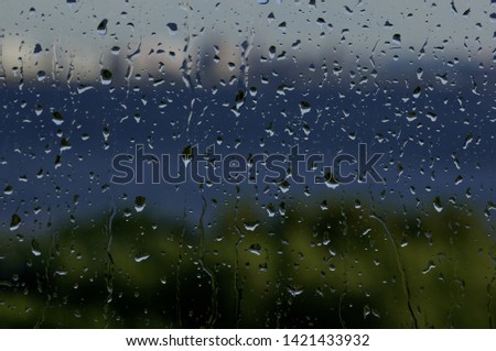 Drops of water on the glass after the rain. Outside the window is a blurred landscape.