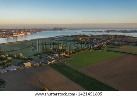 Felixstowe container port, the River Orwell and Harwich from the air above Shotley peninsula at sunset and moonrise. Shotley Gate and Harwich is to the right of the picture.