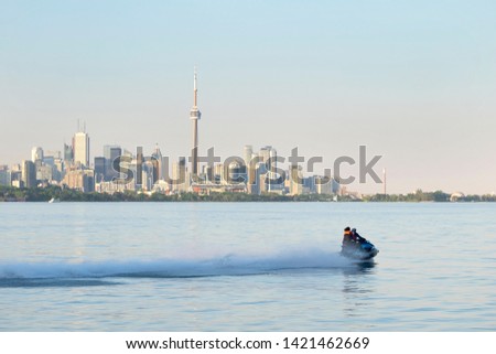 Man riding water motorcycle jet ski on Lake Ontario. Sunny day, Toronto city skyline with CN Tower in the background out of focus. Summer sports and activities concept. Space for copy.