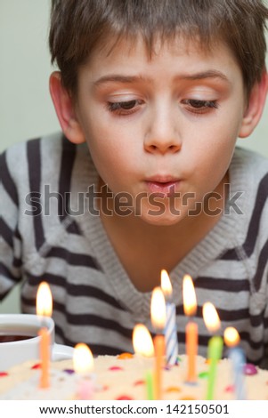 Young boy blowing out candles on birthday cake