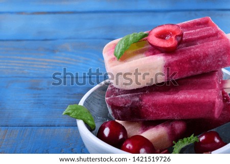 Fruit and berry popsicles with cherries against the blue background