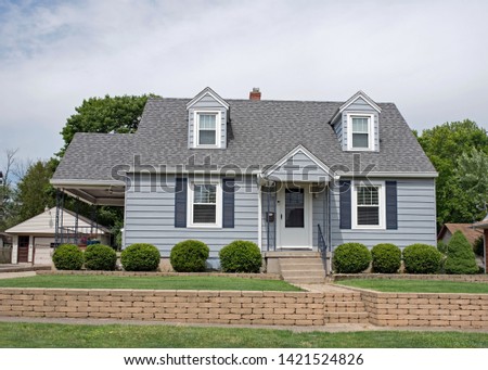 Little Blue Cape Cod House with Tan Brick Wall Royalty-Free Stock Photo #1421524826
