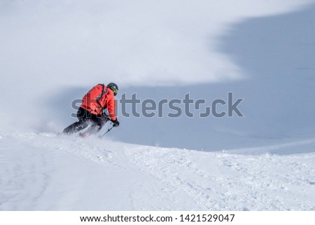Freeride skier in snow covered mountain slope in winter making first tracks in untouched virgin snow