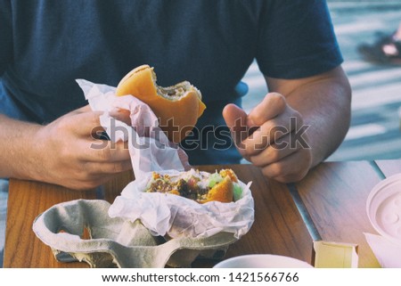 American cheese burger in man hand in cafe. Eating in a restaurant and enjoying delicious fast food. Toned image.