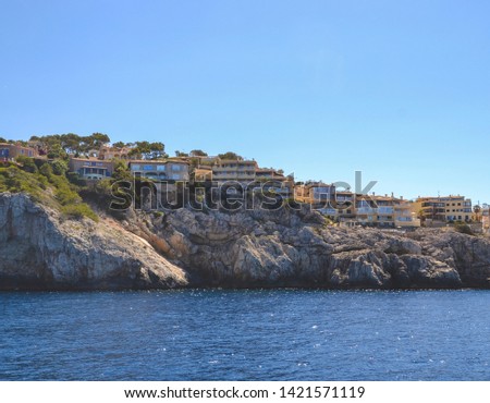 View of the stone beach with small yellow houses on the Palma de Mallorca. Blue sky and sea as main color of picture matching to yellow shade. Memory card from vacation. Part of Spain. 