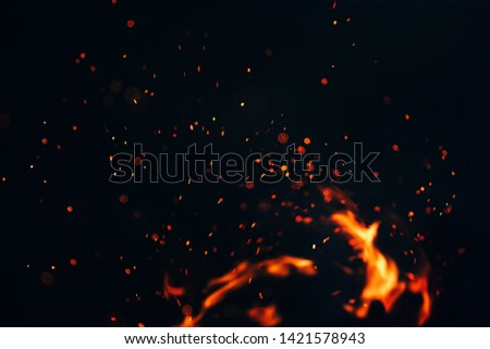 beautiful photo, the texture of the campfire at night, the flare of sparks in the air on a black background