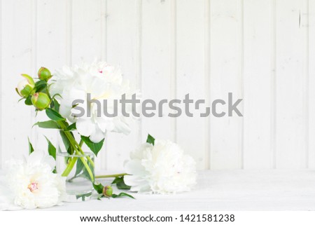 White tender background with peonies on the wooden table, copy space
